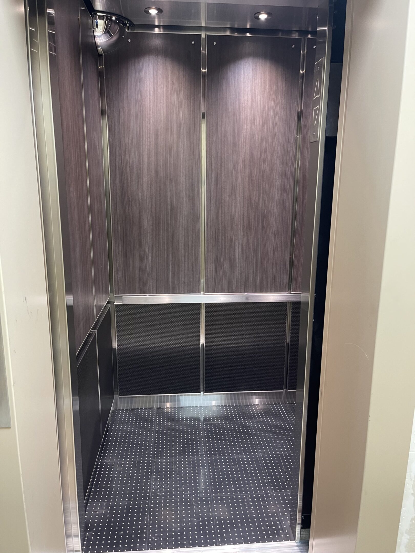 Elevator cab interior featuring walnut & charcoal millwork by NYC Elevator Cab Co.