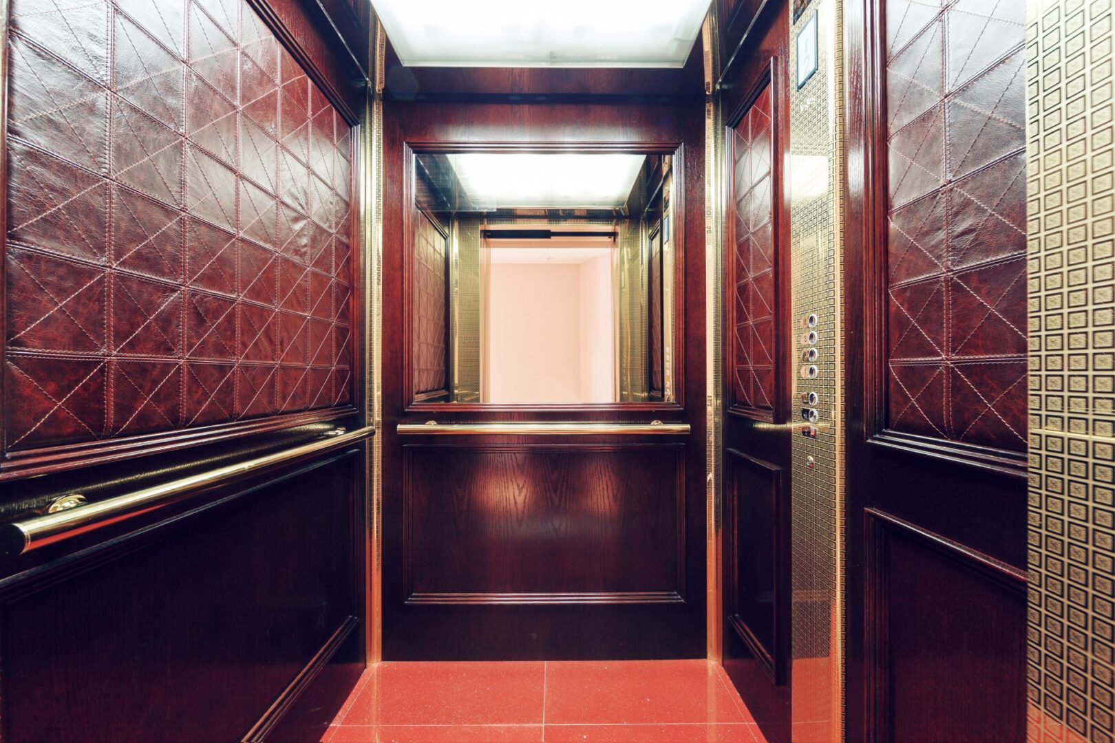 Renovated elevator cab interior with wood millwork panels and warm lighting by NYC Elevator Cab Co.